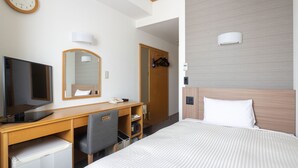 A hotel room with a bed, a desk with a computer, a chair, a TV, a mirror, and a wardrobe.