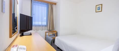 A hotel room with a bed, a desk with a telephone, a television, and a chair.