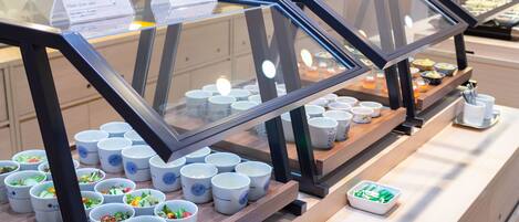 Zona de bufé con diferentes alimentos y recipientes.