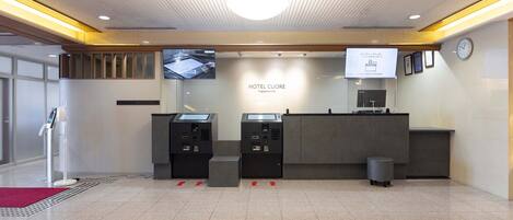 A hotel reception area with a check-in counter, a digital display, and a reception desk.