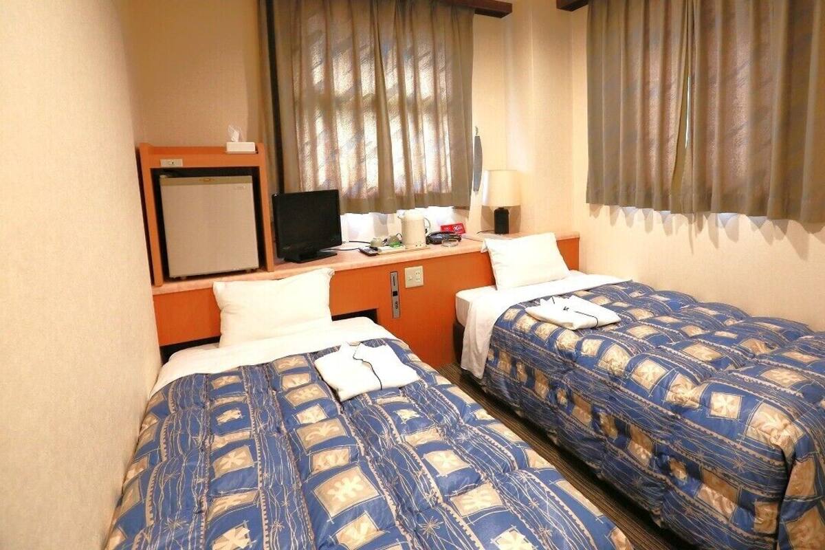 Una habitación de hotel con dos camas, un escritorio con computadora y televisión.