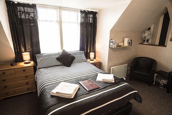Une chambre bien rangée, avec un lit, des tables de chevet, une chaise et un radiateur.