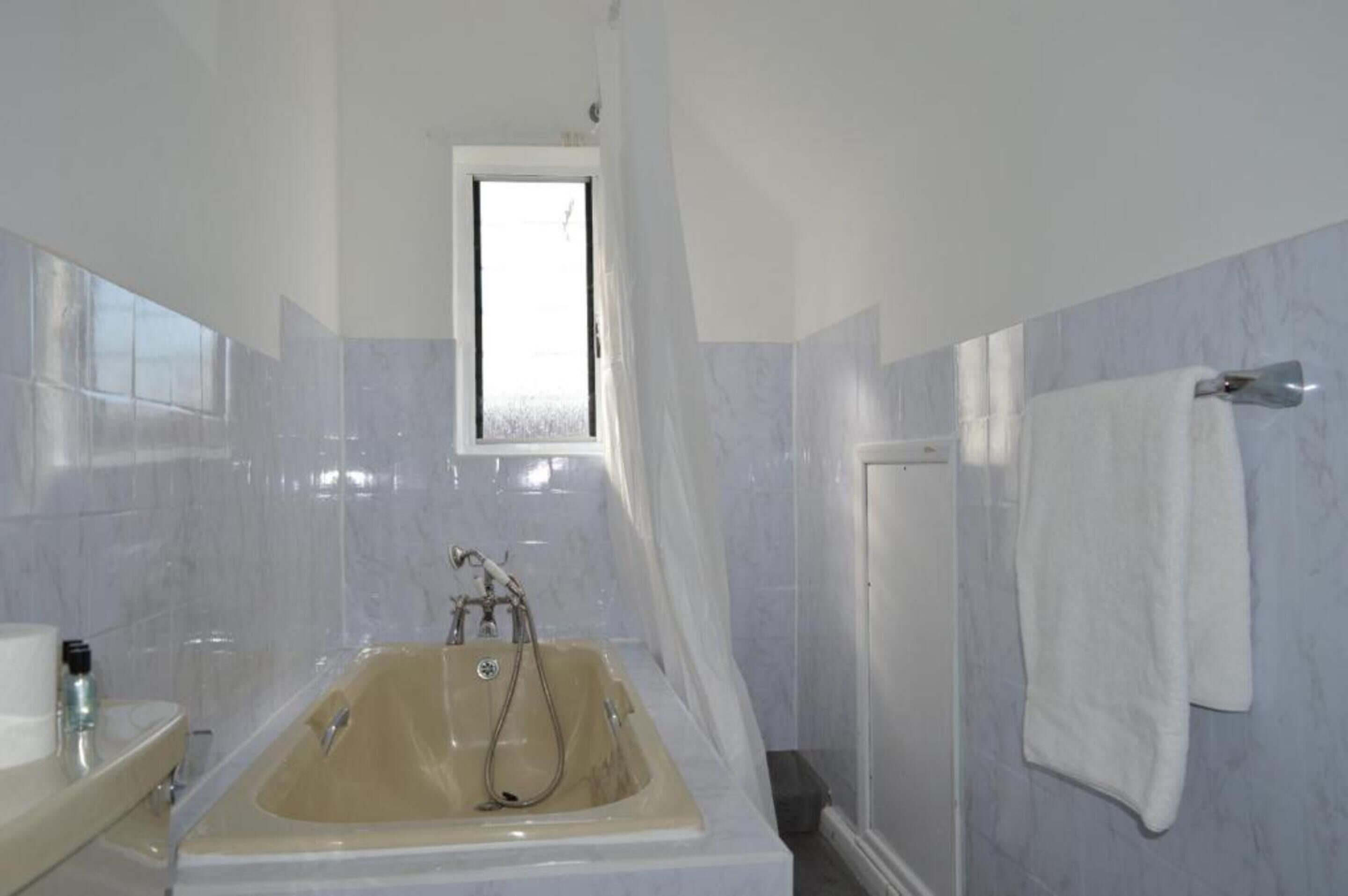 Une salle de bain avec une baignoire, une fenêtre et un porte-serviettes.