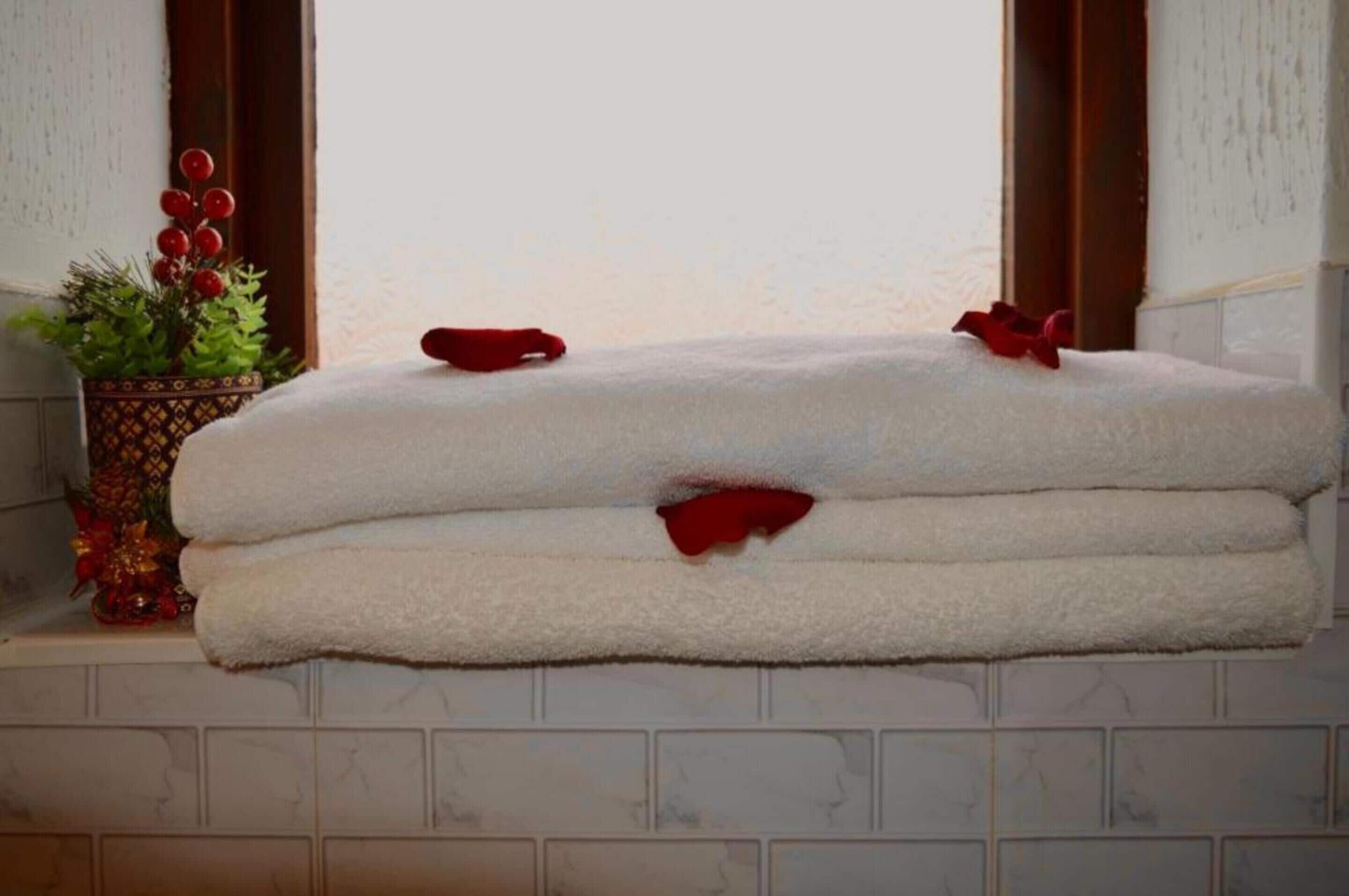 A stack of white towels with red bows on a shelf.