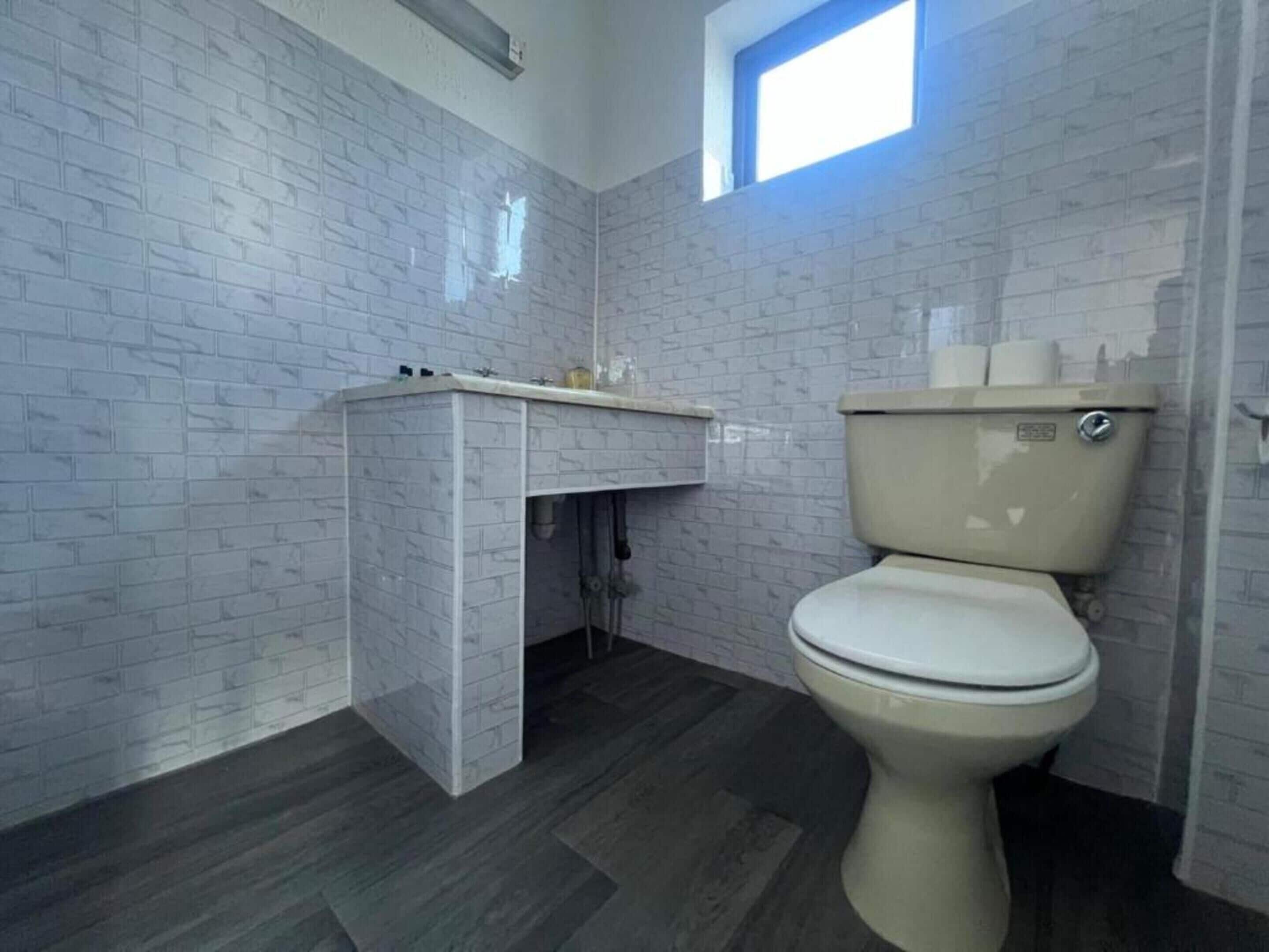 Un bagno con il water, un lavandino e una finestra.