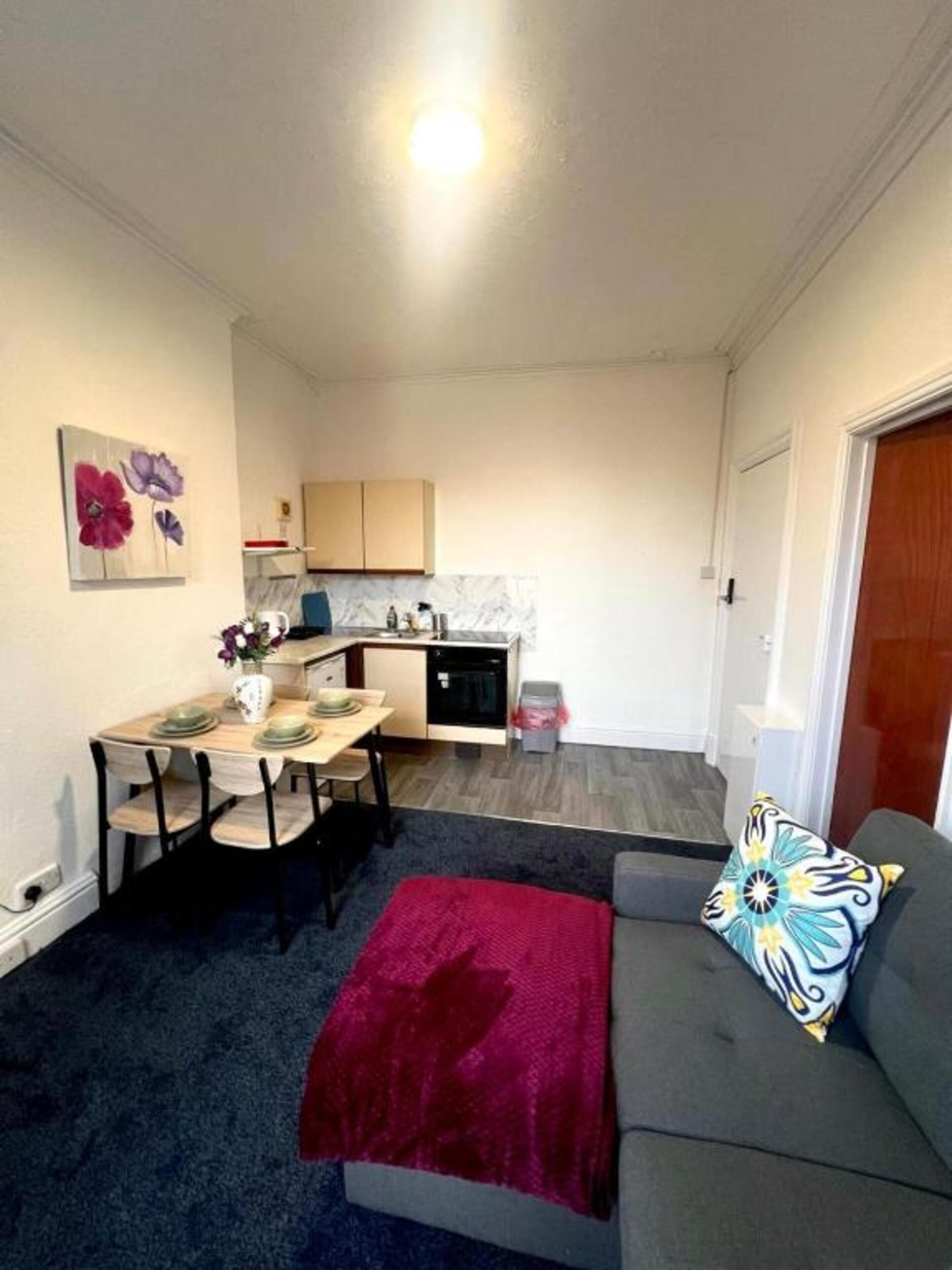 A compact living space with a dining area, kitchenette, and a sofa with a decorative pillow.