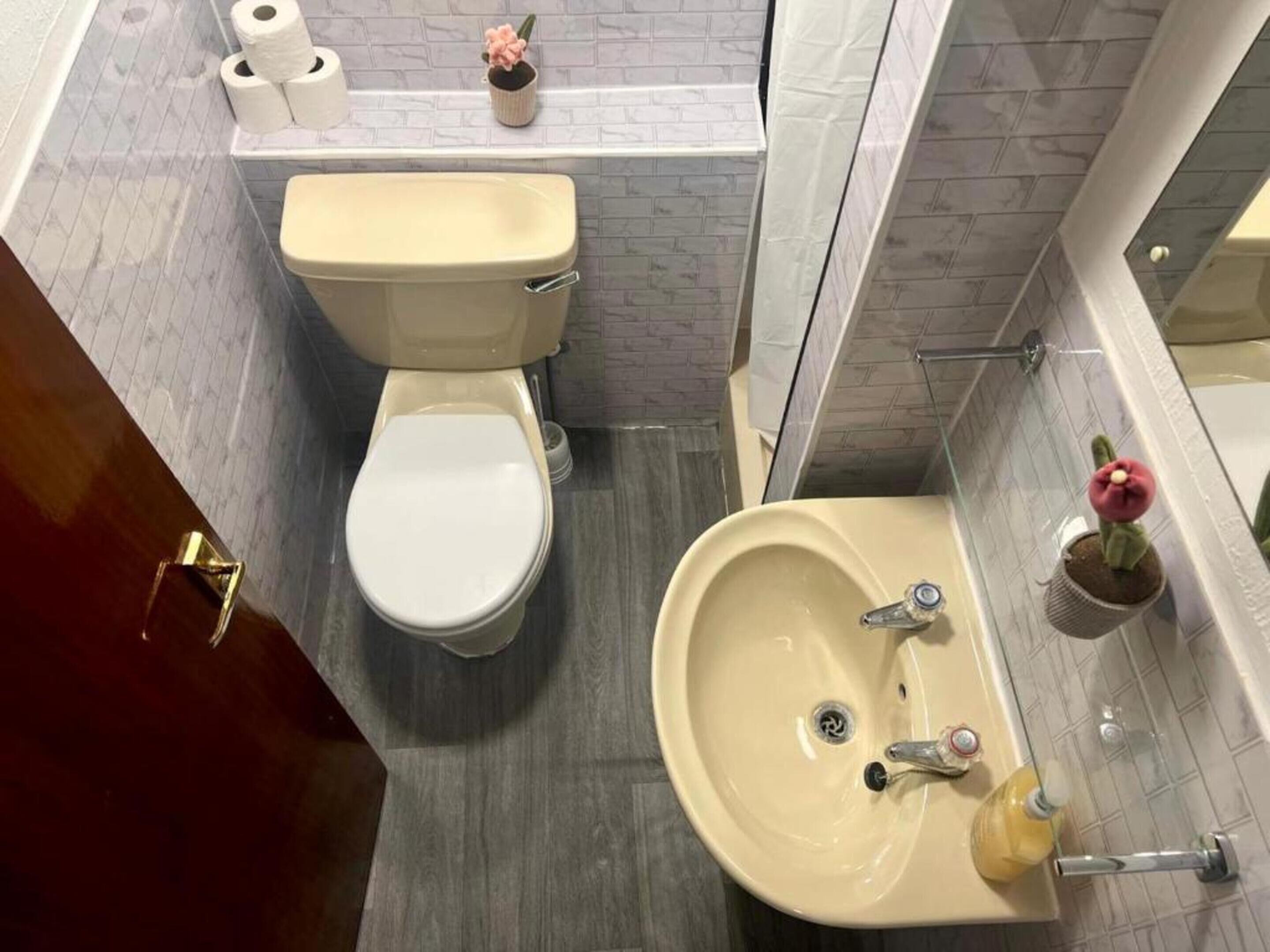 A bathroom with a toilet, sink, and a mirror.