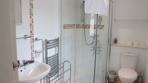 A modern bathroom with a glass-enclosed shower, a white sink, and a toilet. - The Homestar (Skegness)