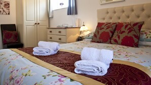A hotel room with a bed, two bedside tables, a wardrobe, and a window with curtains. - The Homestar (Skegness)