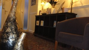 A lobby with a patterned carpet, a black console table, a wicker sofa, and two large vases. - The Monsell Hotel (Skegness)