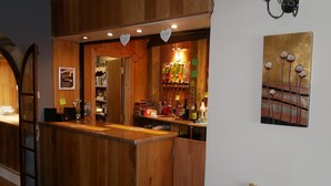 A wooden bar area with a counter, shelves with bottles, and a painting on the wall. - The Monsell Hotel (Skegness)
