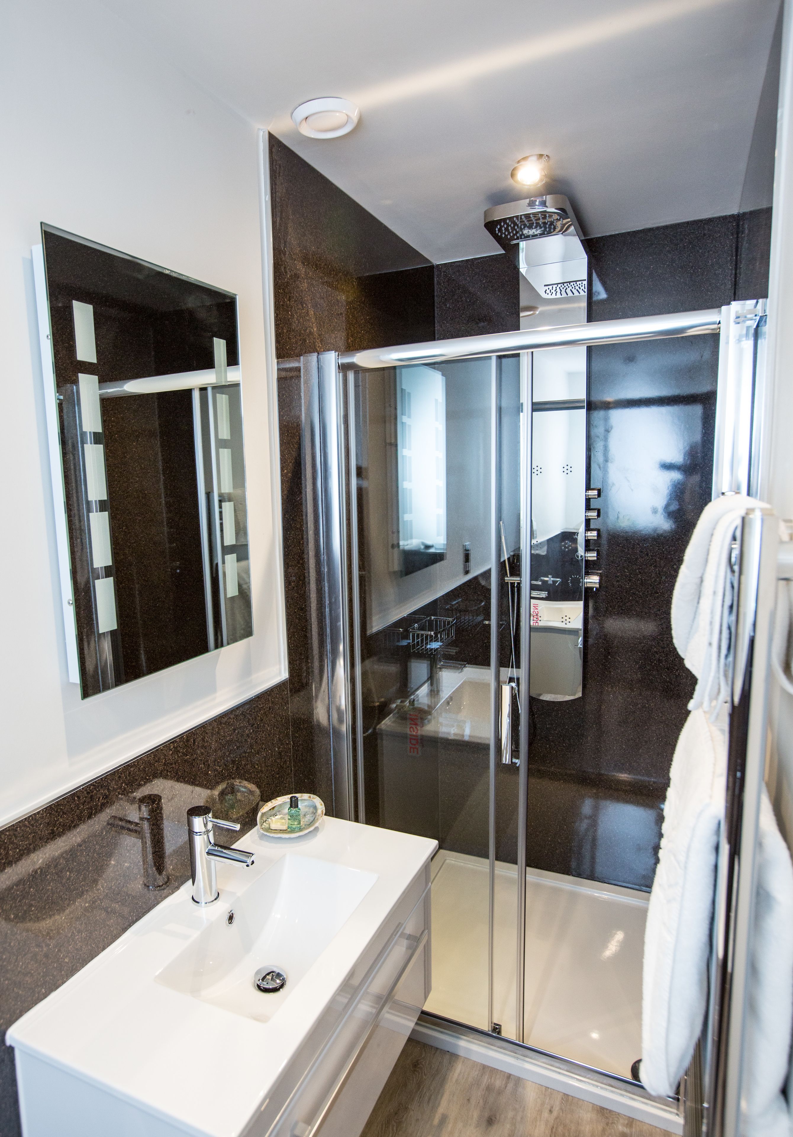 A modern bathroom with a glass-enclosed shower, a white sink, and a large mirror.