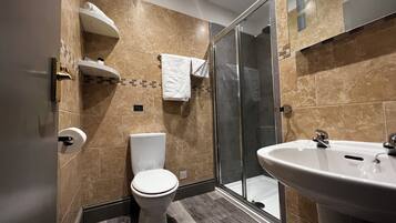 Een moderne badkamer met toilet, douche en wastafel.