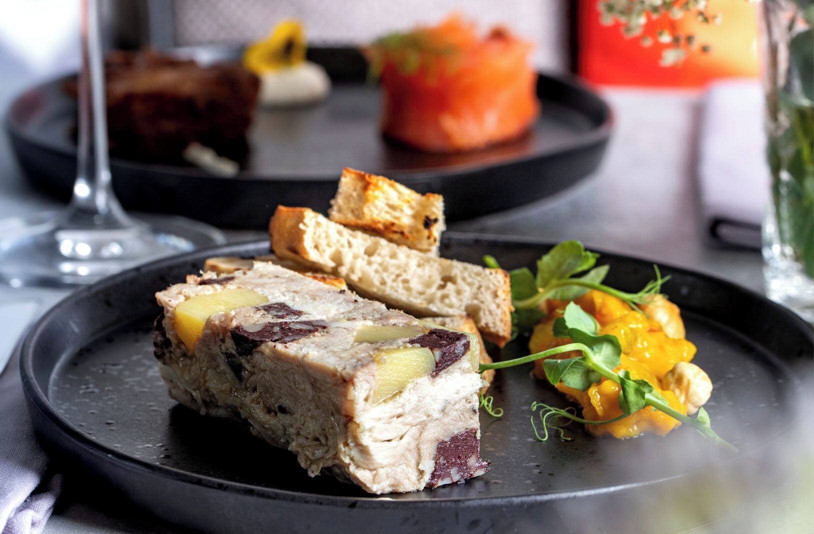 A plate with a slice of meatloaf, some bread, and a side of vegetables.