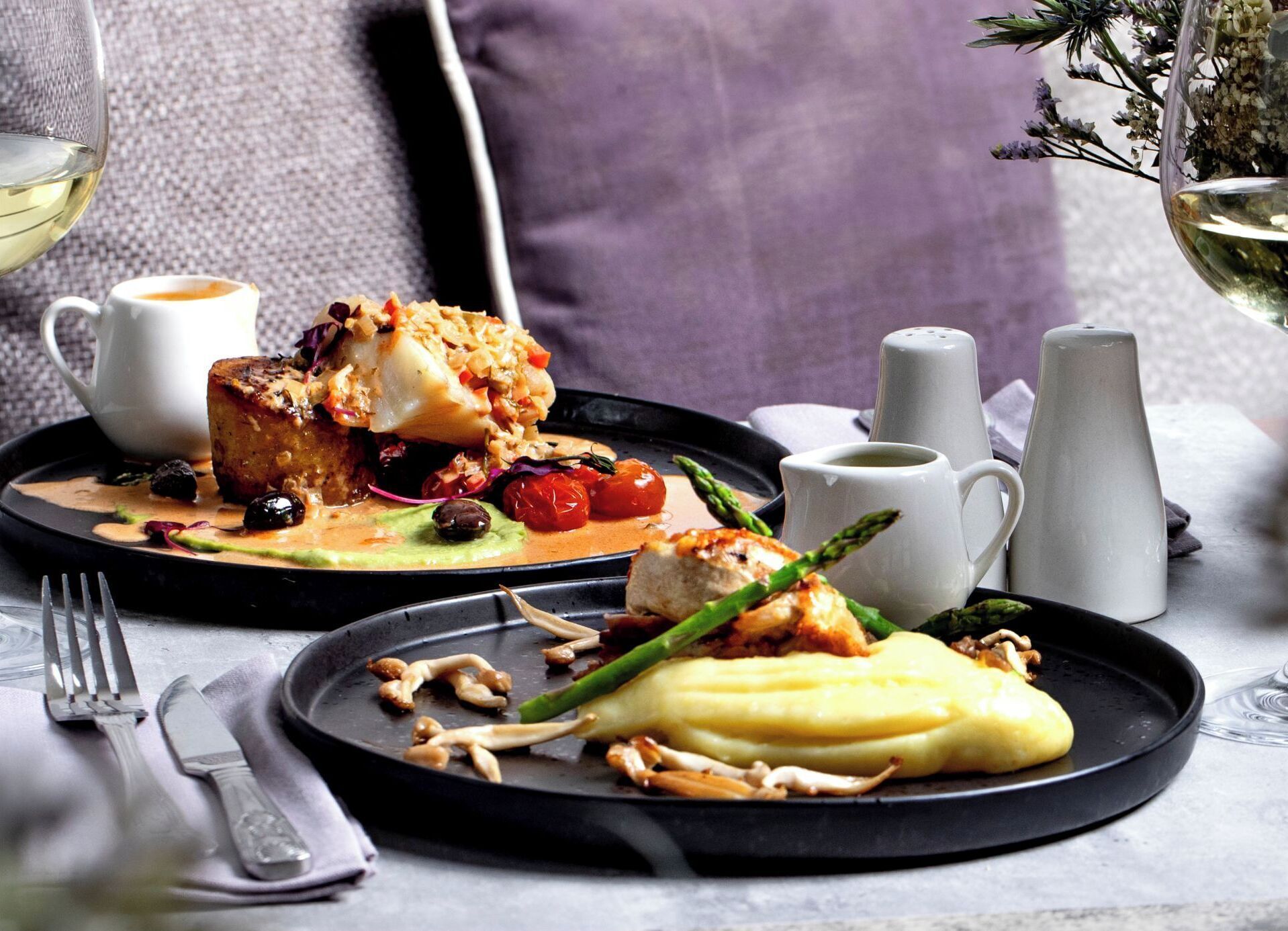 A dining table with plates of food, a white mug, and salt and pepper shakers.