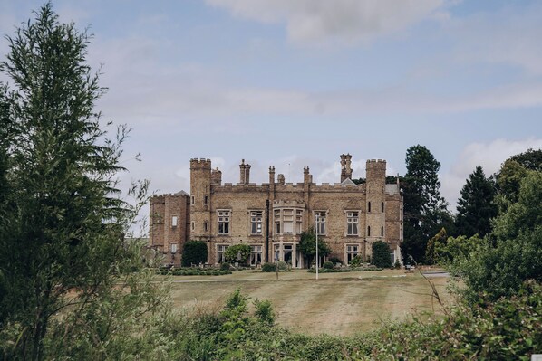 A large, historic building with multiple towers and a symmetrical facade, surrounded by greenery. - Cave Castle Hotel  (Brough)