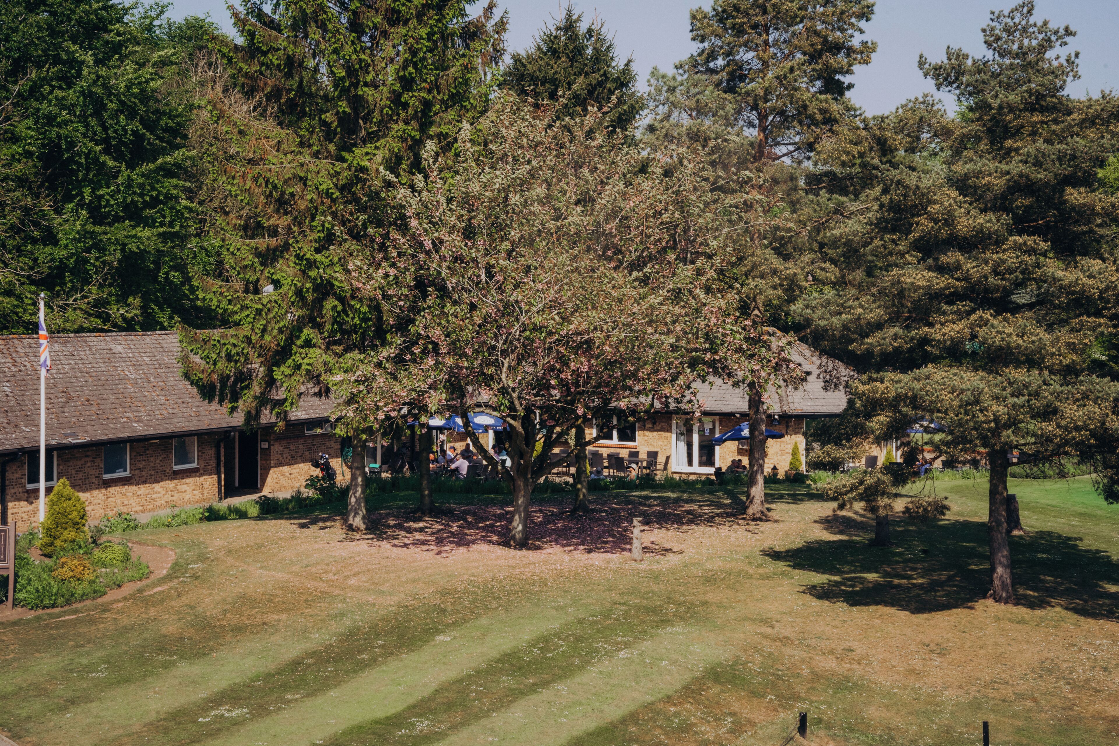 A building with a brick exterior, surrounded by trees and a grassy area.