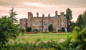 A large, historic building with multiple towers and turrets, surrounded by well-maintained gardens and trees. - Cave Castle Hotel  (Brough)
