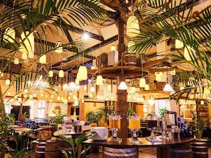 Um restaurante com balcão central, diversas luminárias pendentes e diferentes opções de assentos.