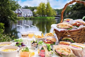 A picnic setup with food and drinks by a lake, including sandwiches, salads, and beverages. - Forest Villa Huis Ten Bosch (Sasebo)