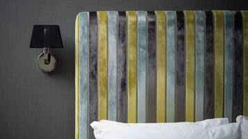 A striped headboard with a round wall-mounted lamp beside it.