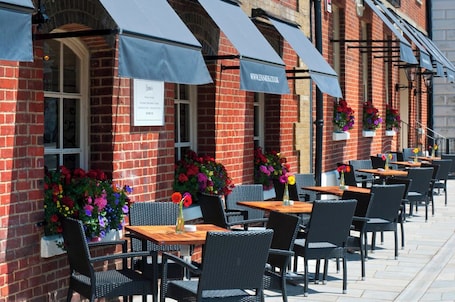 A brick building with outdoor seating, awnings, and flower boxes.