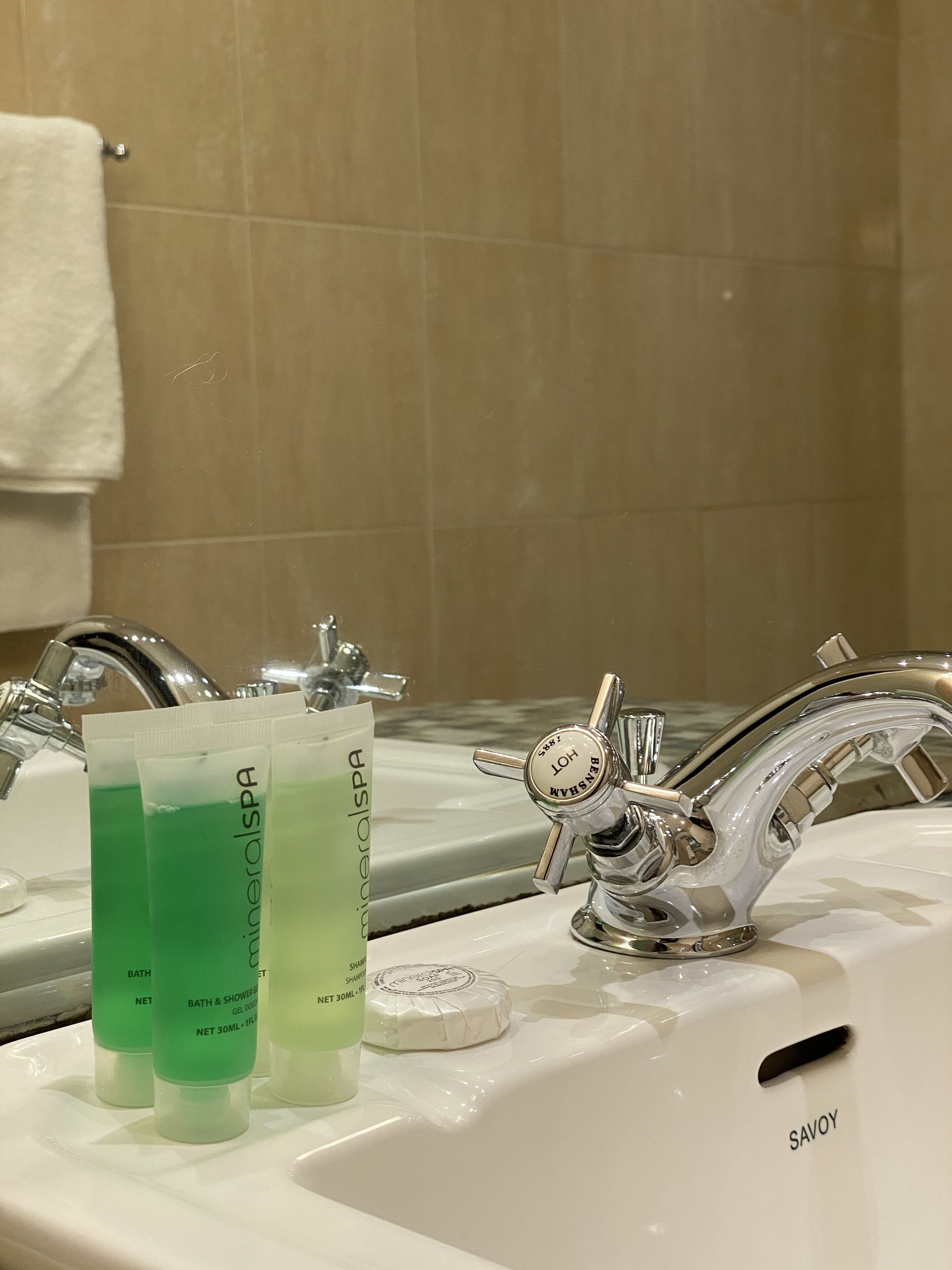 A bathroom sink with two bottles of bath and shower gel, a soap bar, and a faucet.