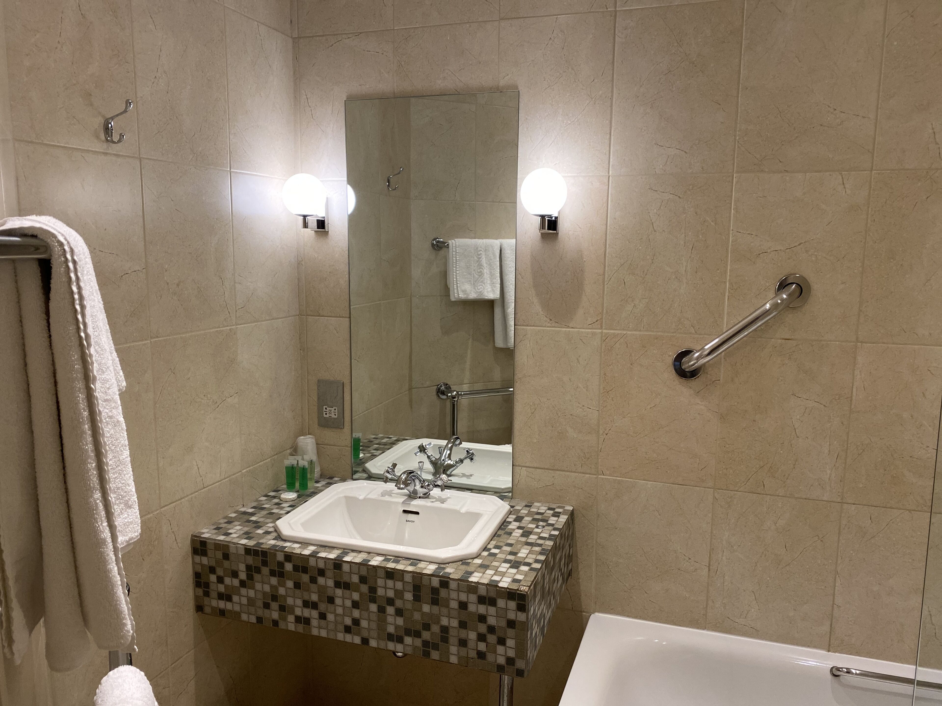 A bathroom with a sink, mirror, and a grab bar.