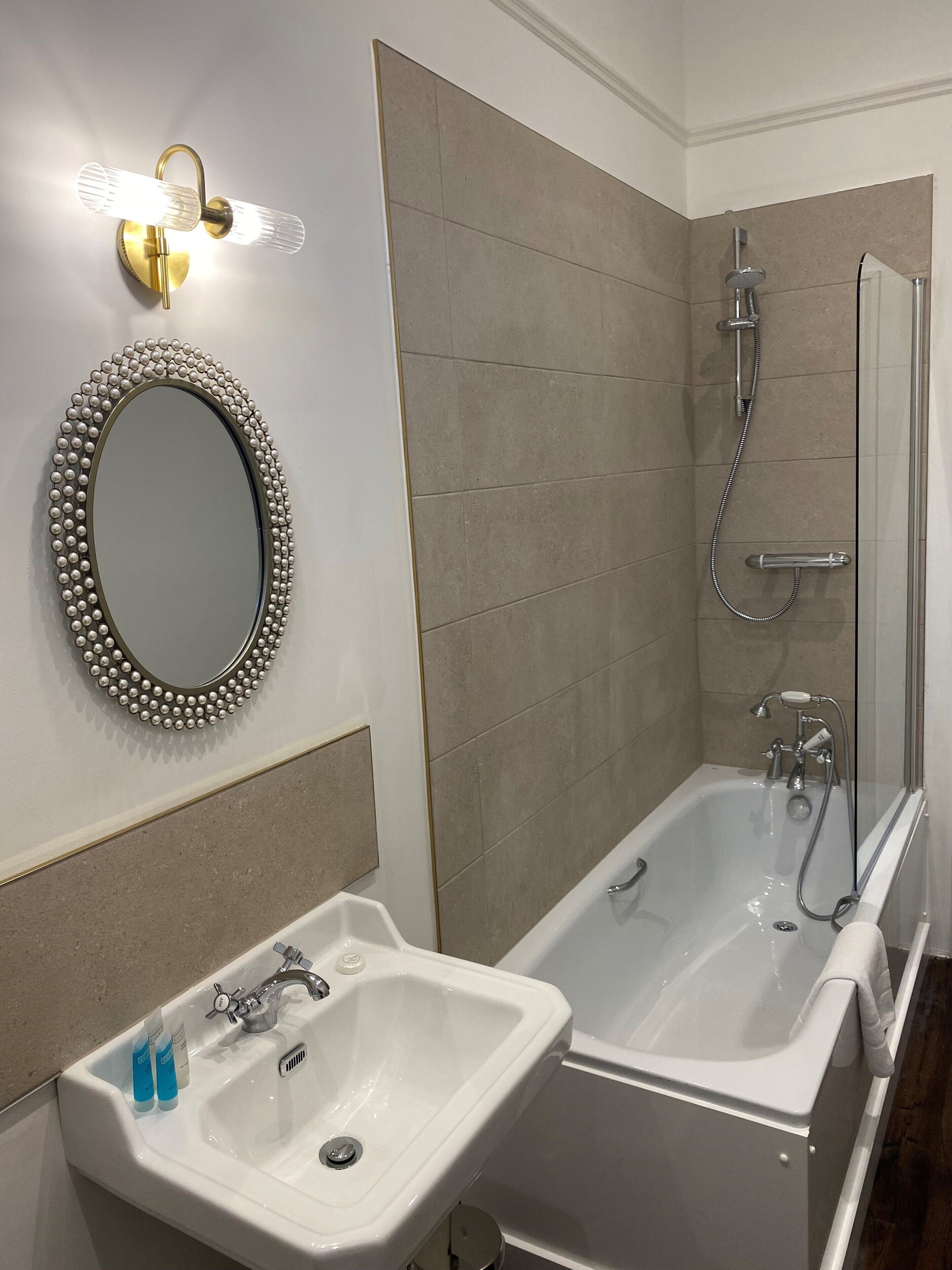 A bathroom with a sink, mirror, and bathtub.