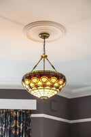 Un candelabro con diseño de vitral colgando de un ventilador de techo.