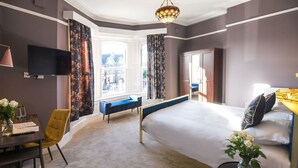 Een moderne hotelkamer met een groot bed, een bureau met stoel, een televisie en uitzicht op het omliggende landschap.
