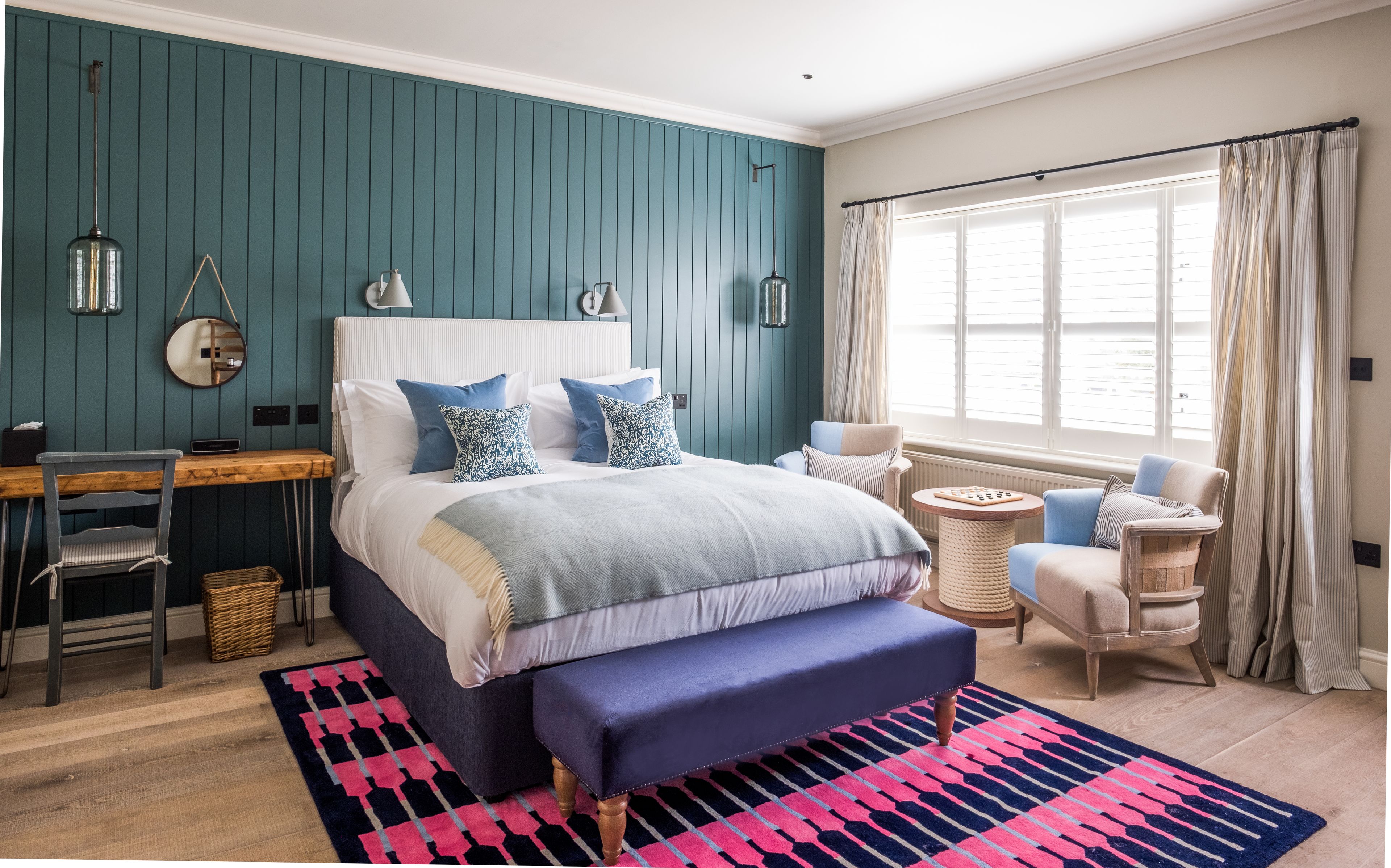 A bedroom with a bed, bedside tables, a desk, and a window with curtains.