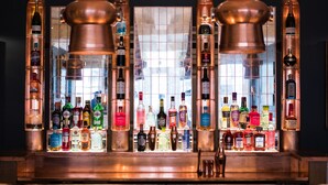 Un espace bar avec un assortiment de bouteilles d’alcool et des éléments décoratifs en cuivre.