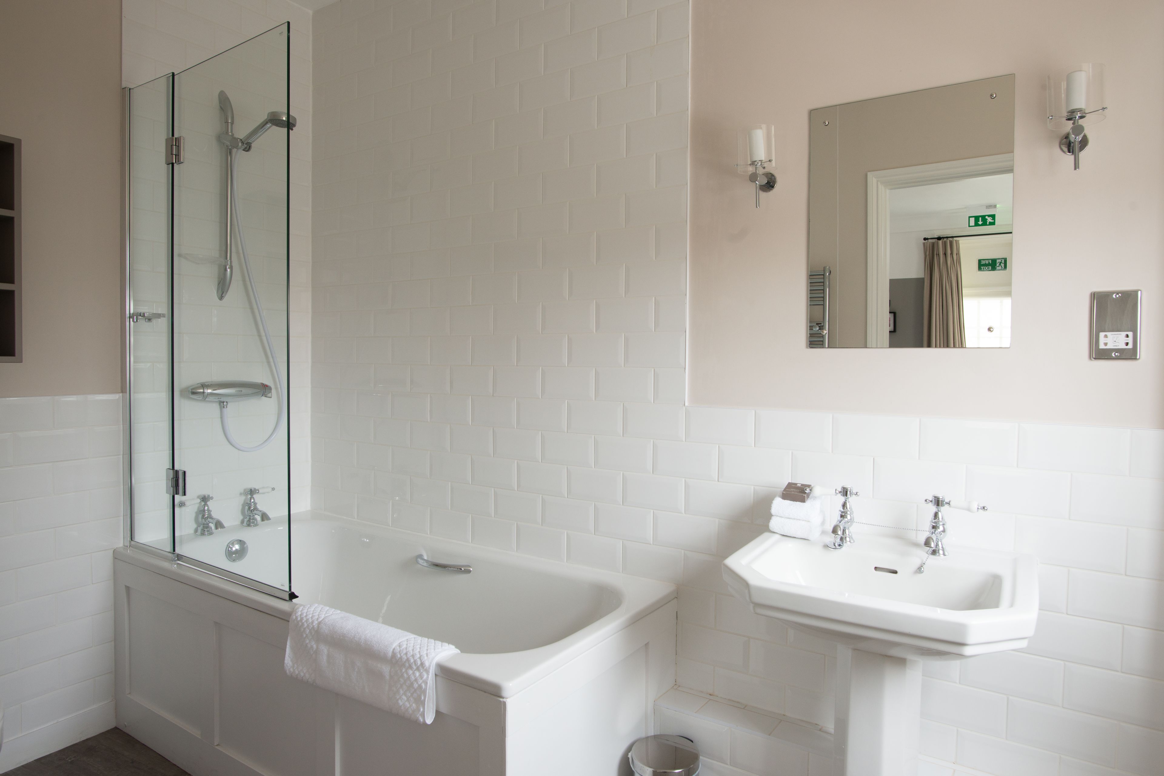 A modern bathroom with a glass-enclosed shower, a standalone bathtub, and a pedestal sink.