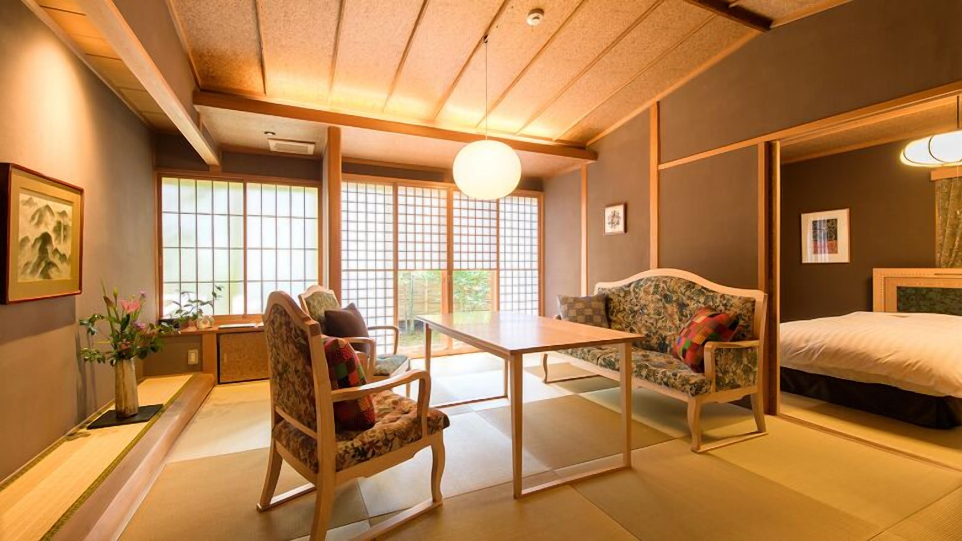 A traditional Japanese-style room with tatami flooring, a low table, two chairs, a sofa, and a bed.