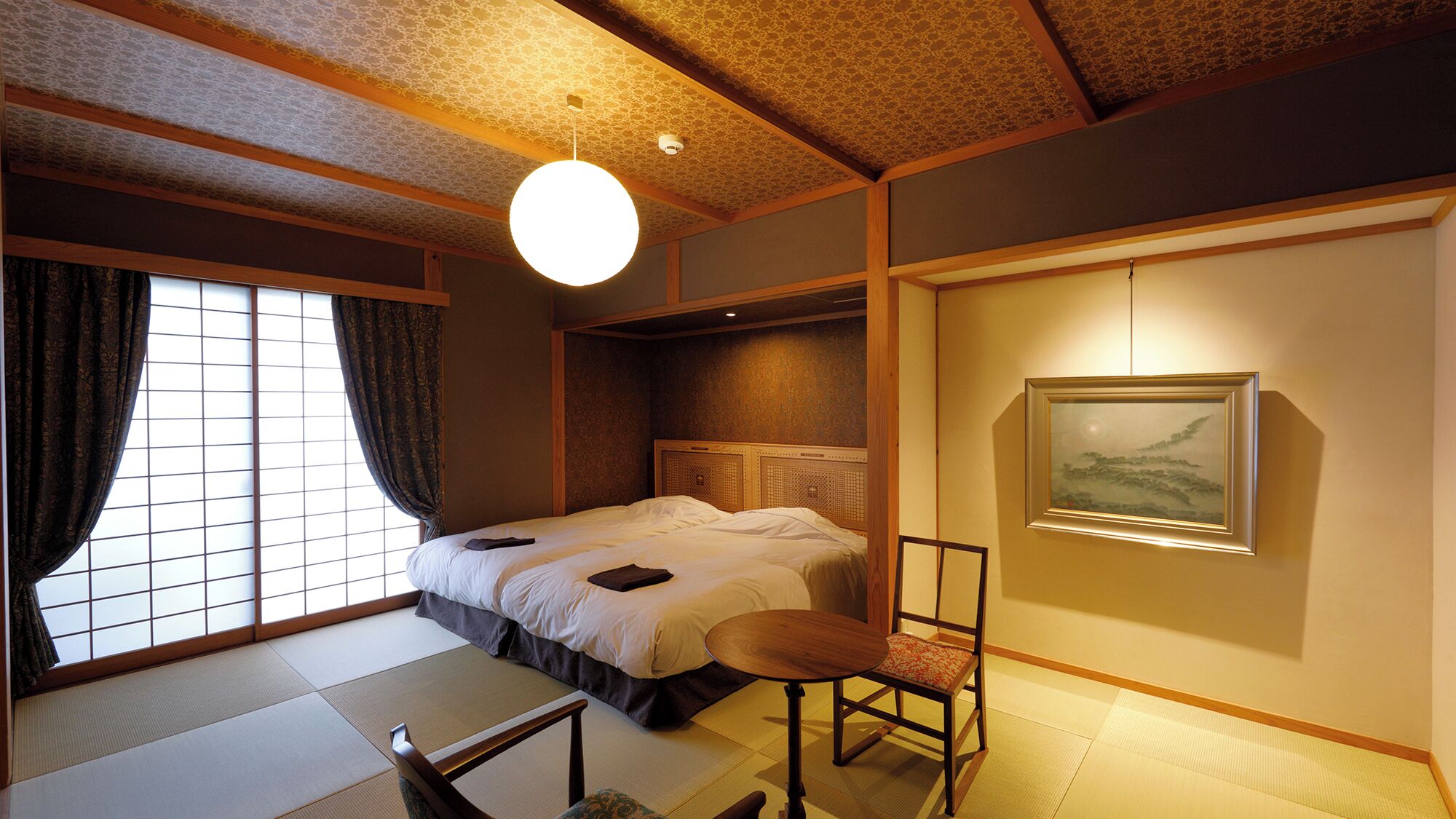 A traditional Japanese-style bedroom with tatami flooring, a bed with white bedding, a wooden chair, and a framed picture on the wall.
