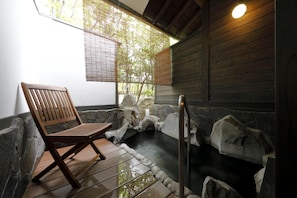 A wooden bench in a stone-walled room with a small pool and a window with bamboo blinds. - Kosumosu (Yufu)