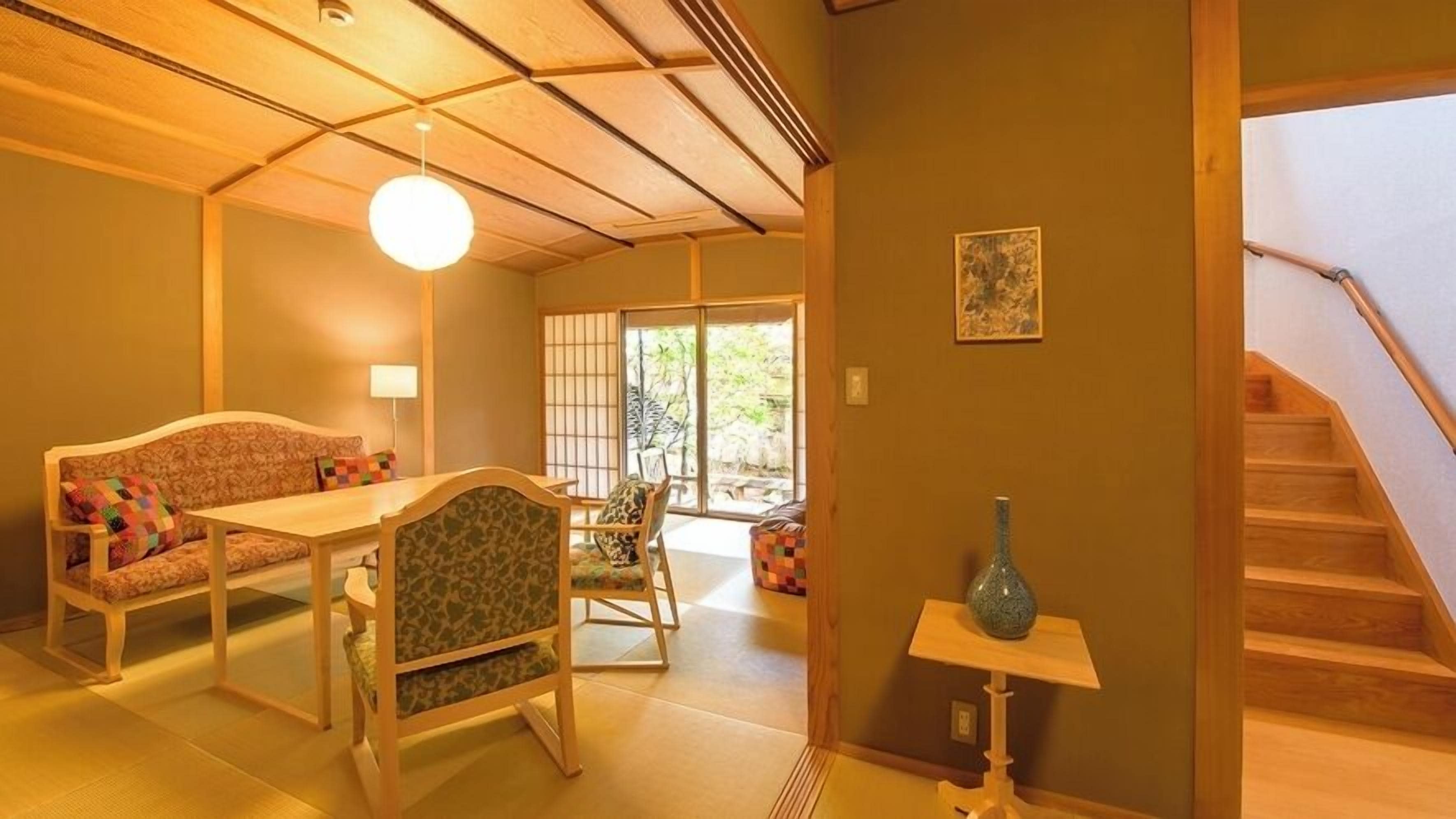 Una habitación tradicional japonesa con suelo de tatami, una mesa baja y un sofá.