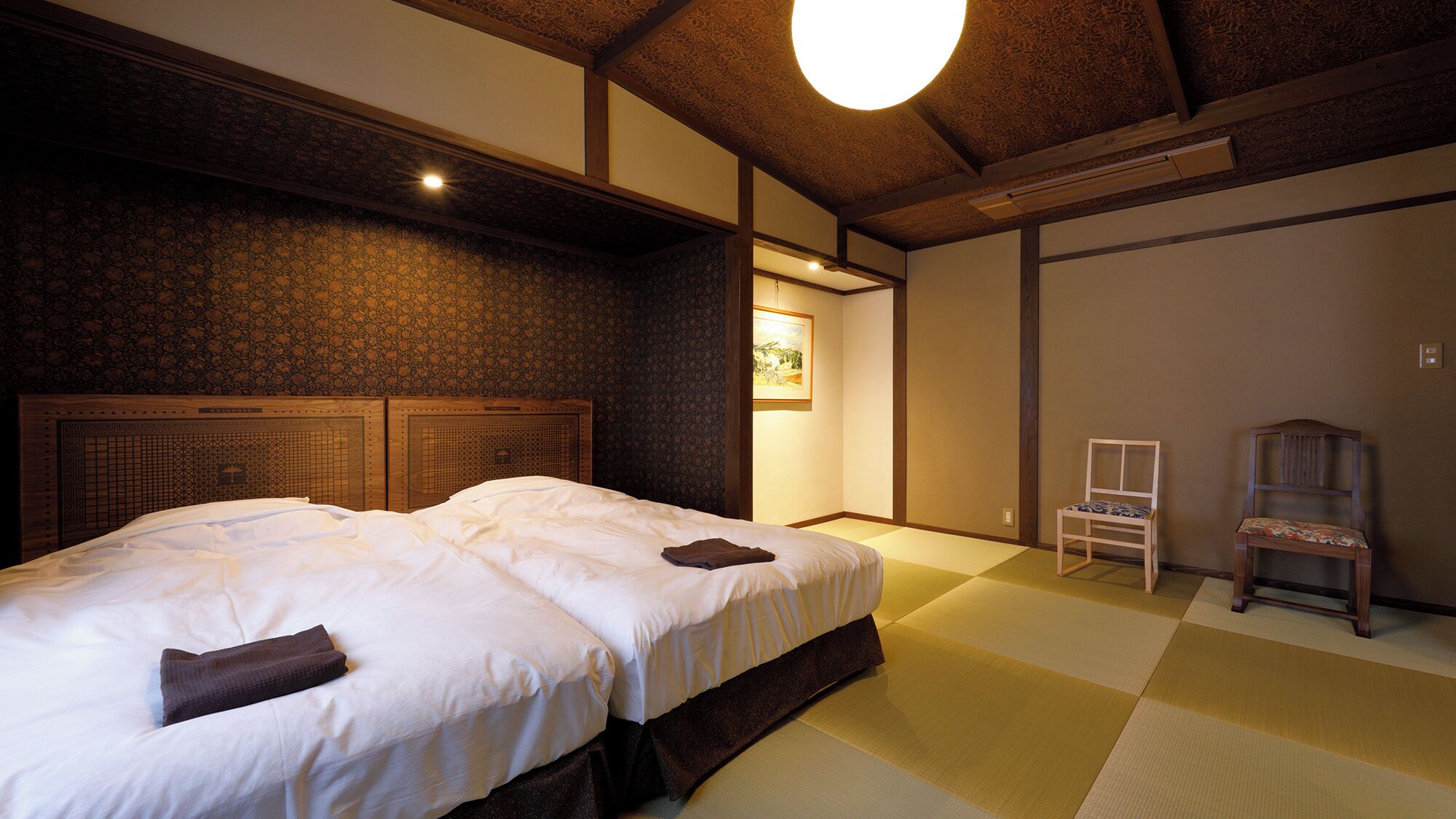 A traditional Japanese-style bedroom with tatami flooring, a low wooden bed frame, and a hanging light fixture.