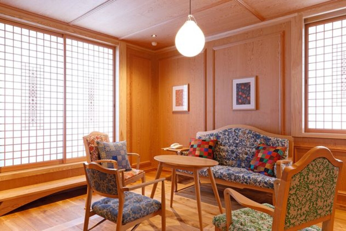 A traditional Japanese room with tatami flooring, a low wooden table, and a sofa with patterned cushions.
