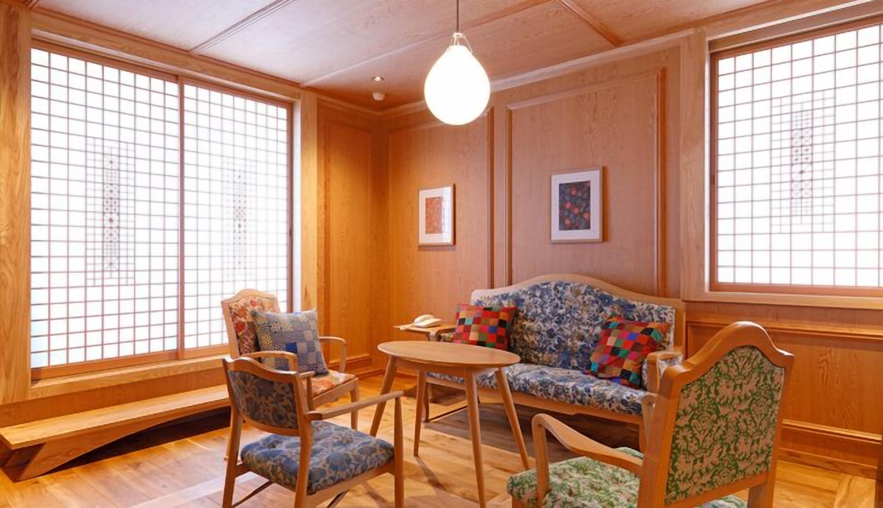 Een traditionele Japanse kamer met tatami vloerbedekking, een lage houten tafel en een bank met gestreepte kussens.