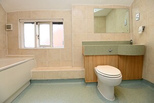 Un baño con bañera, lavamanos, inodoro y ventana.