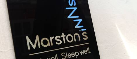 A black sign with white and blue text reading "Marston's" and "Eat well. Sleep well."