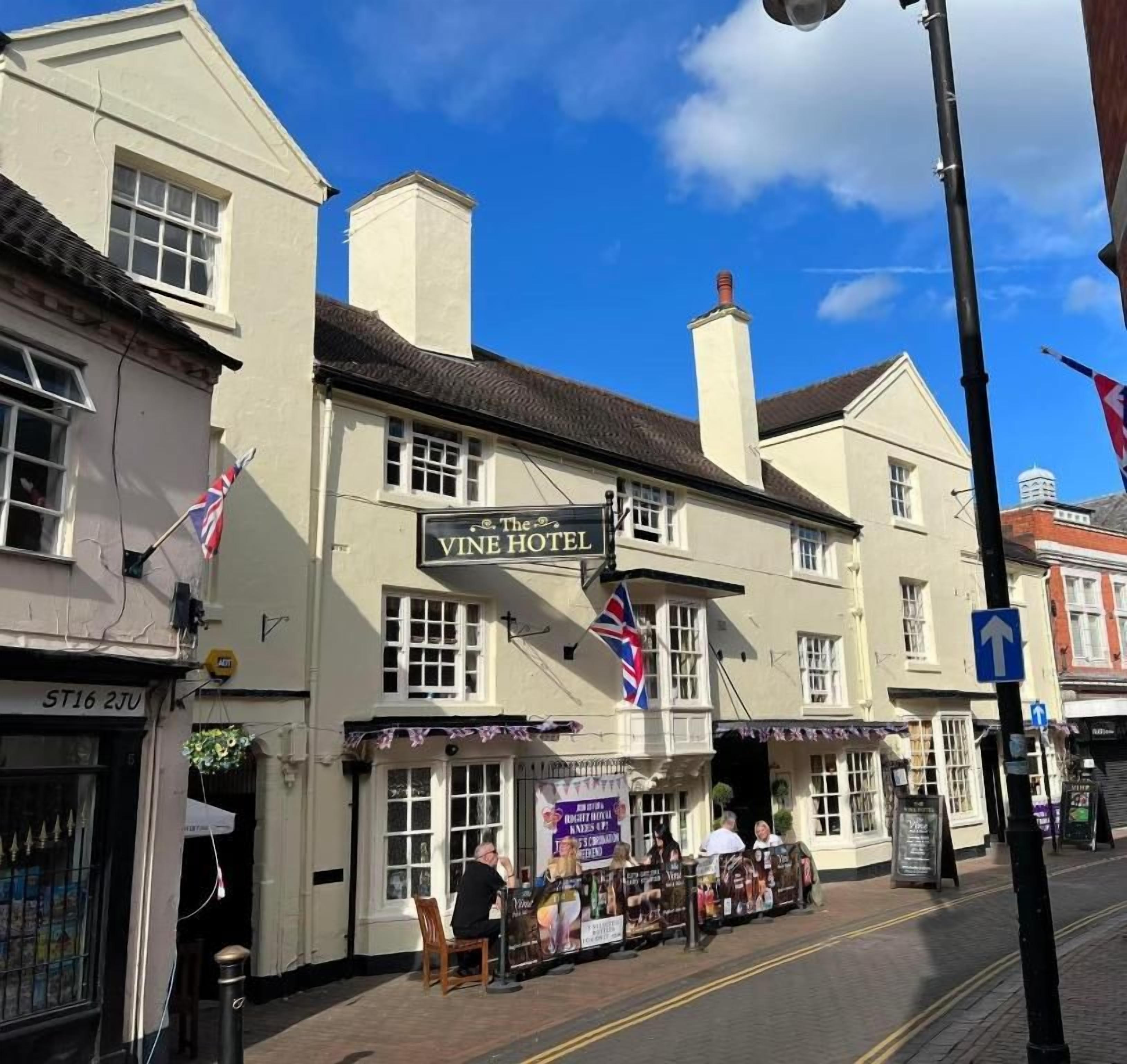 A building with a sign reading 'The Vine Hotel' and a flag outside.