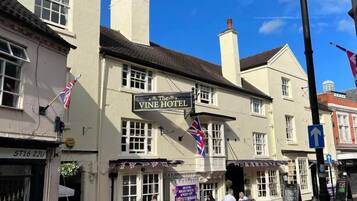 Um edifício com uma placa que diz 'The Vine Hotel' e uma bandeira do lado de fora.