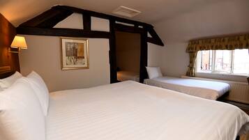 Habitación de hotel con dos camas, techo de madera, ventana con cortinas y un cuadro en la pared.