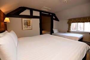 Habitación de hotel con dos camas, techo de madera, ventana con cortinas y un cuadro en la pared.