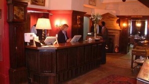 A reception desk with a lamp, a vase with flowers, and a sign indicating a dining room. - The George Of Stamford (Stamford)