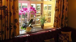 A room with a large window, a sofa, and potted plants. - The George Of Stamford (Stamford)