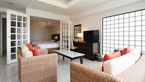 A hotel room with a bed, a TV, wicker furniture, and a large window. - Hotel Royal Marine Palace Ishigakijima (Ishigaki)